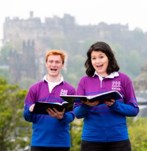NYCOS members wearing purple and blue branded rugby shirts while singing